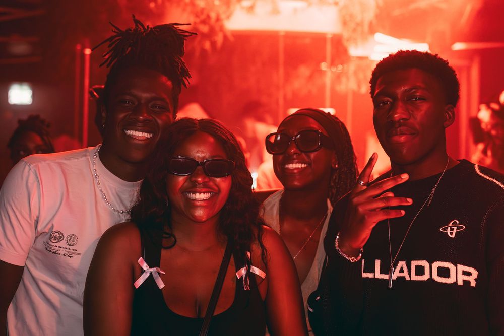 People dancing and having fun at a nightclub with red lighting and a vibrant party atmosphere.