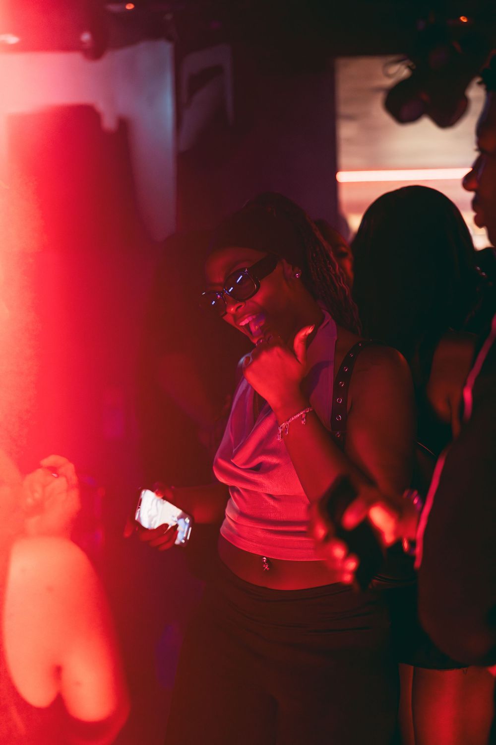 Silhouettes of people dancing in a nightclub under dramatic red lighting and dark shadows.