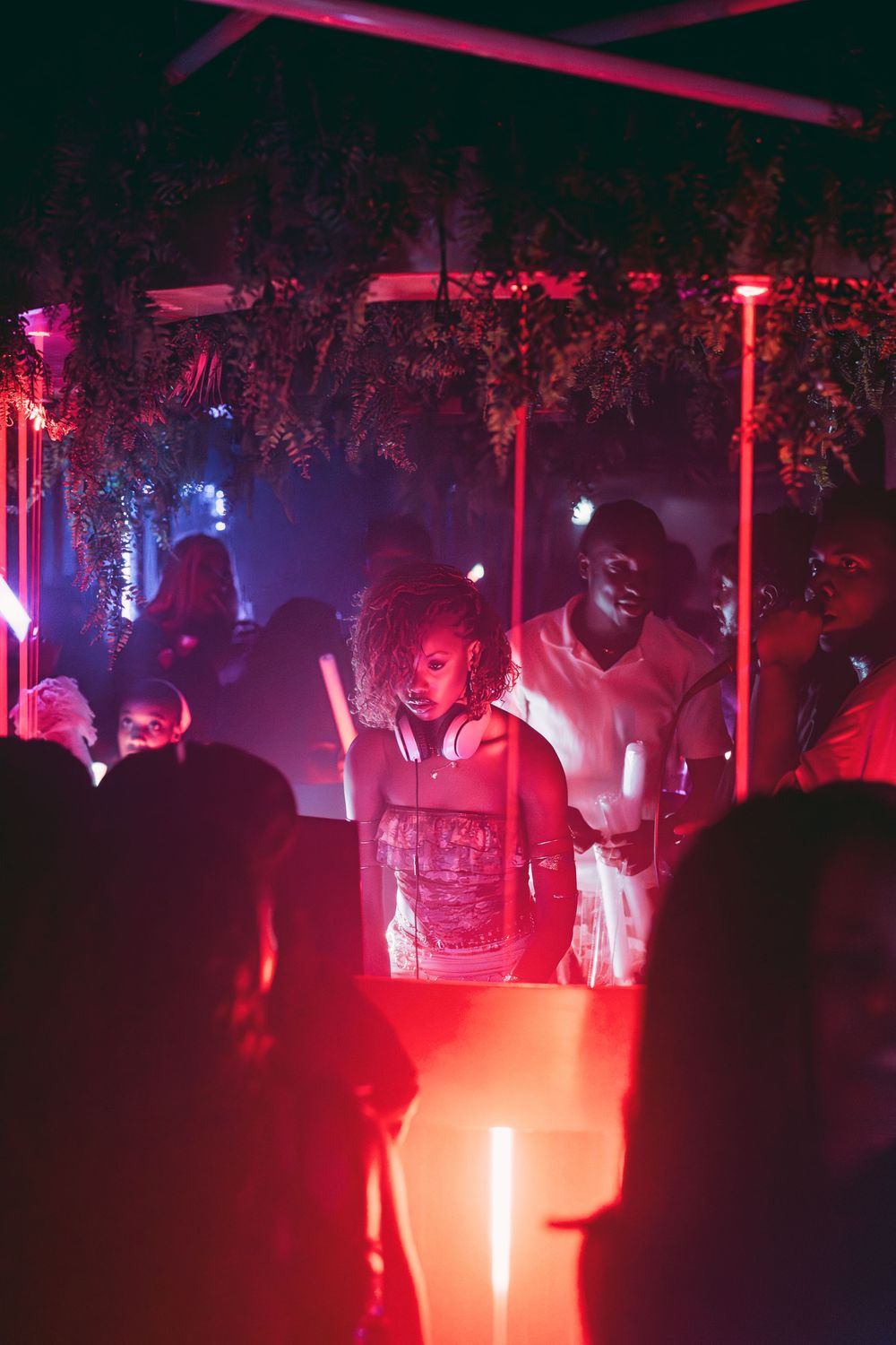 People dance and socialize at a nightclub illuminated by vibrant red and blue lighting.