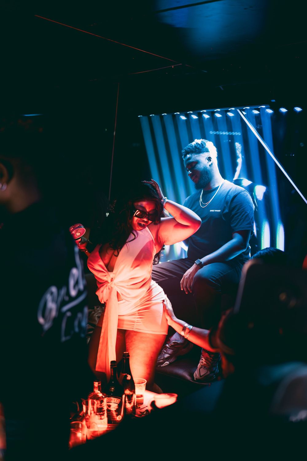 Musicians perform on stage with dramatic red and blue lighting creating a moody atmosphere during a live concert.