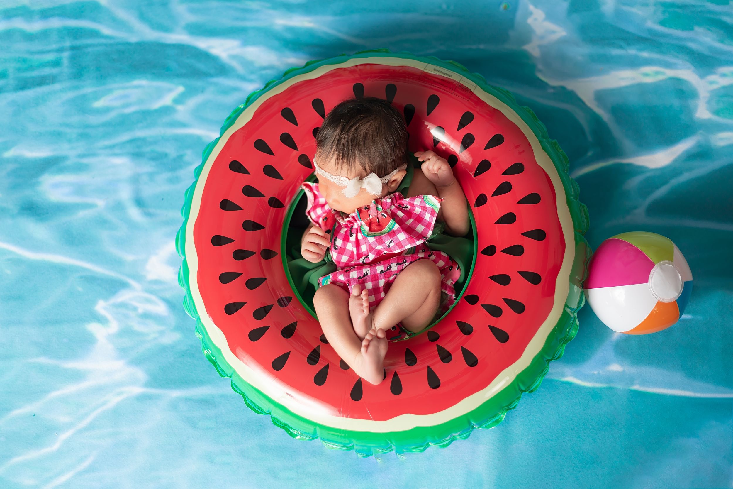 A series of watermelon pool floats in a turquoise swimming pool creates a fun summer scene.