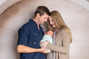 A couple shares an intimate moment while holding a coffee mug against a neutral backdrop.