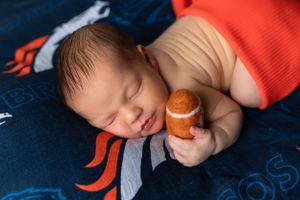 Sleeping peacefully on a blue blanket with orange designs while holding a small toy or plushie.