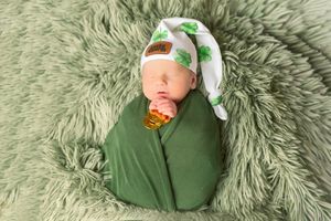 A newborn baby wearing a green onesie lies on a soft, fluffy green blanket in a series of connected photos.