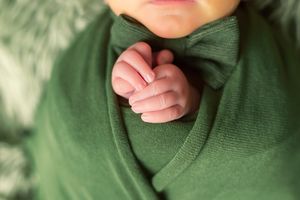Close-up view of tiny clasped hands against a soft green knit sweater.