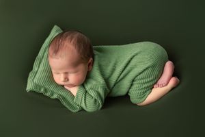 A series of six green-tinted newborn photos showing a sleeping baby wrapped in matching knit fabric against dark background.