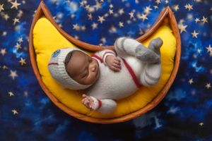 A series of five crescent moon shaped baby photos against a starry blue background creates a dreamy nursery display.