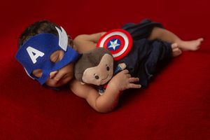 A series of photos showing a baby lying on a red backdrop wearing a Captain America superhero costume and shield.