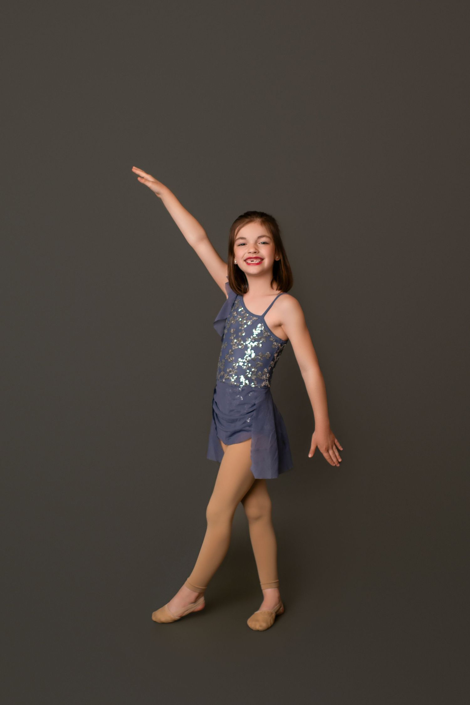 Young dancer in blue leotard strikes dynamic poses against dark backdrop.