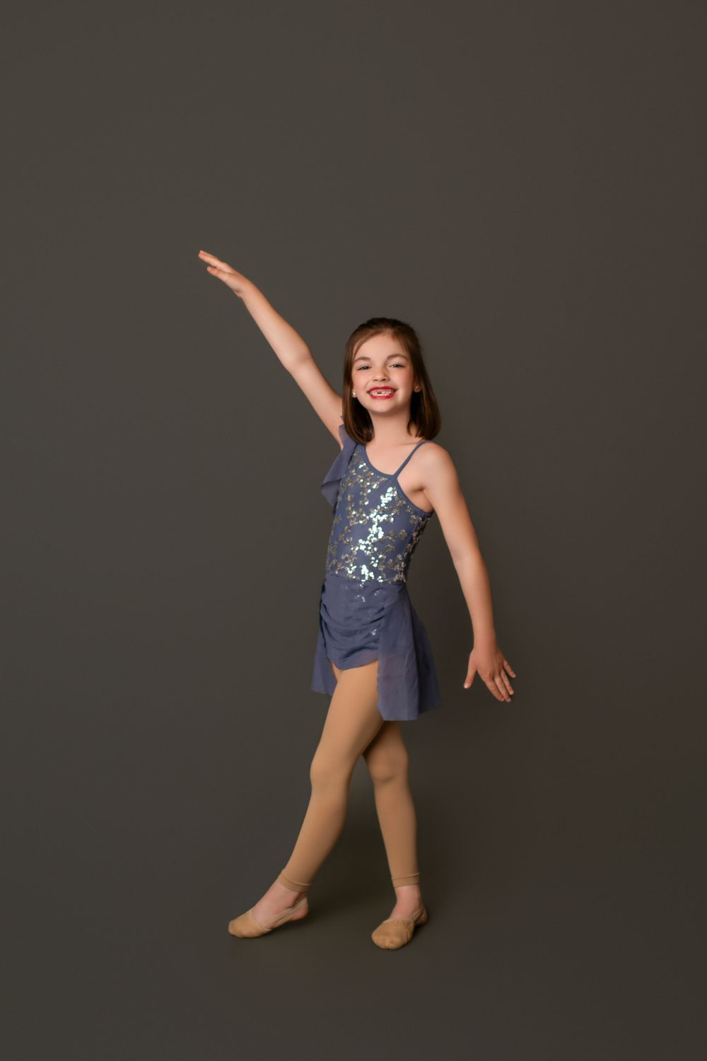 Young dancer in blue leotard strikes dynamic poses against dark backdrop.