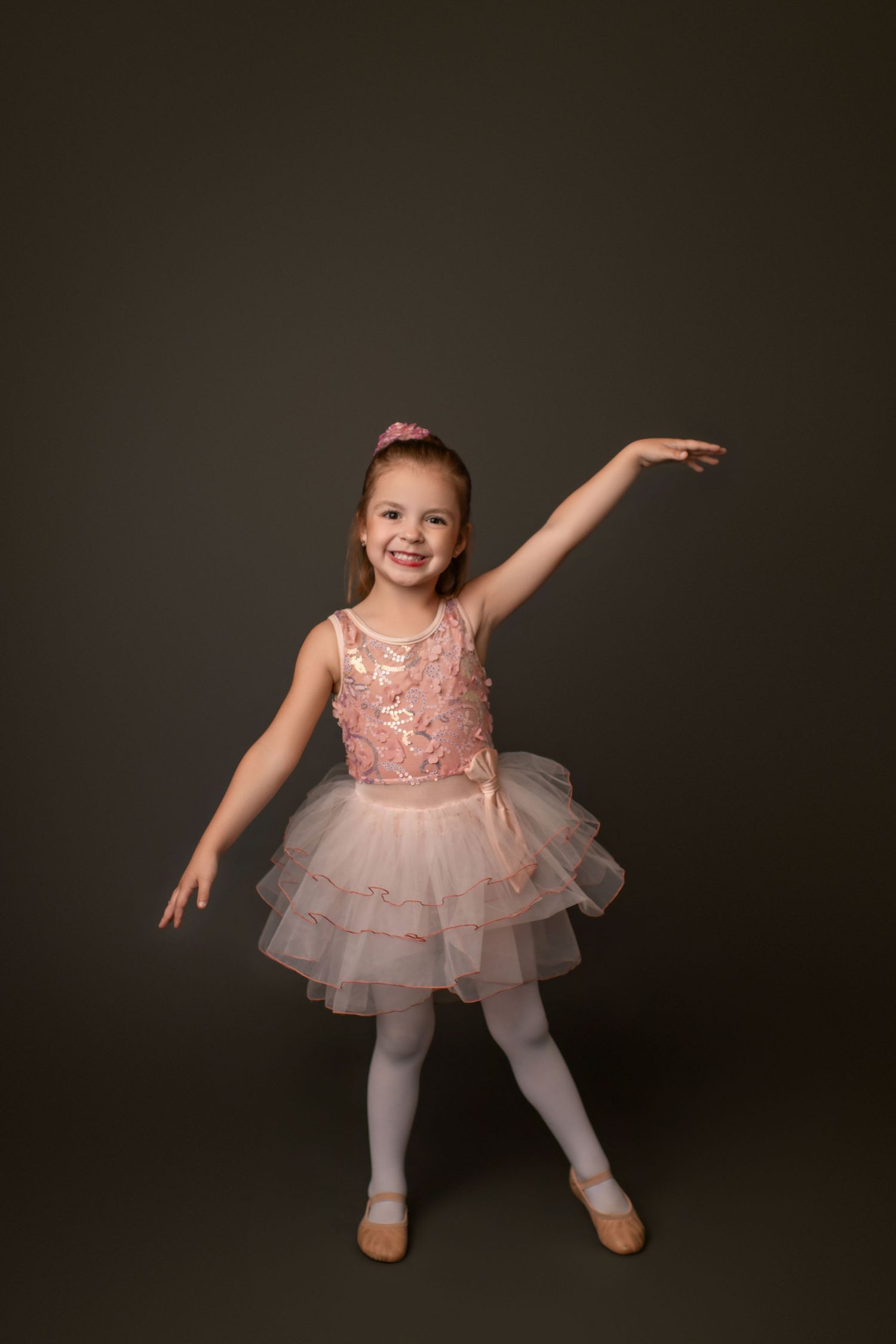 Dancer in pink tutu dress performs graceful moves during studio photoshoot.