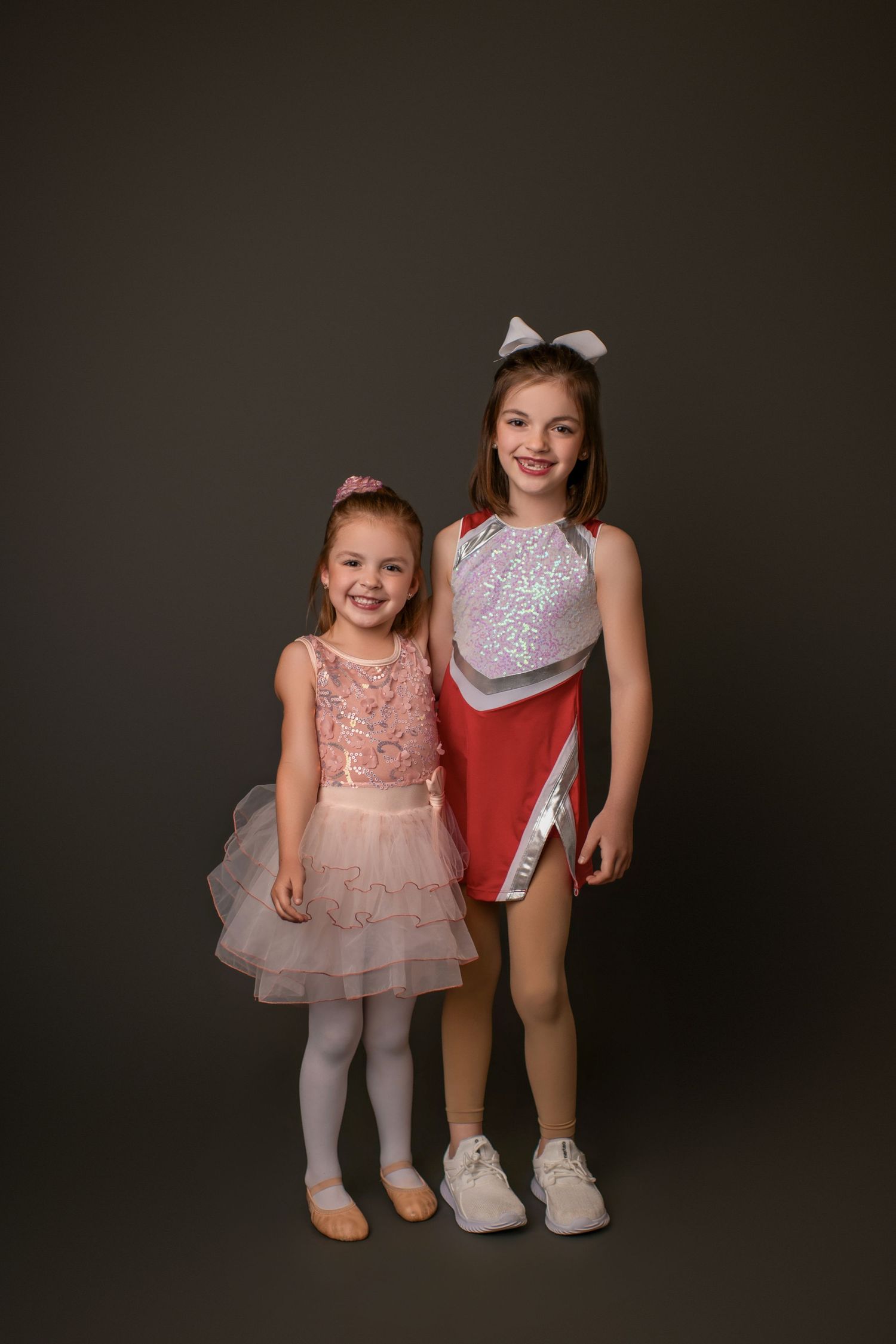 Two dancers in performance costumes pose together against a dark background.