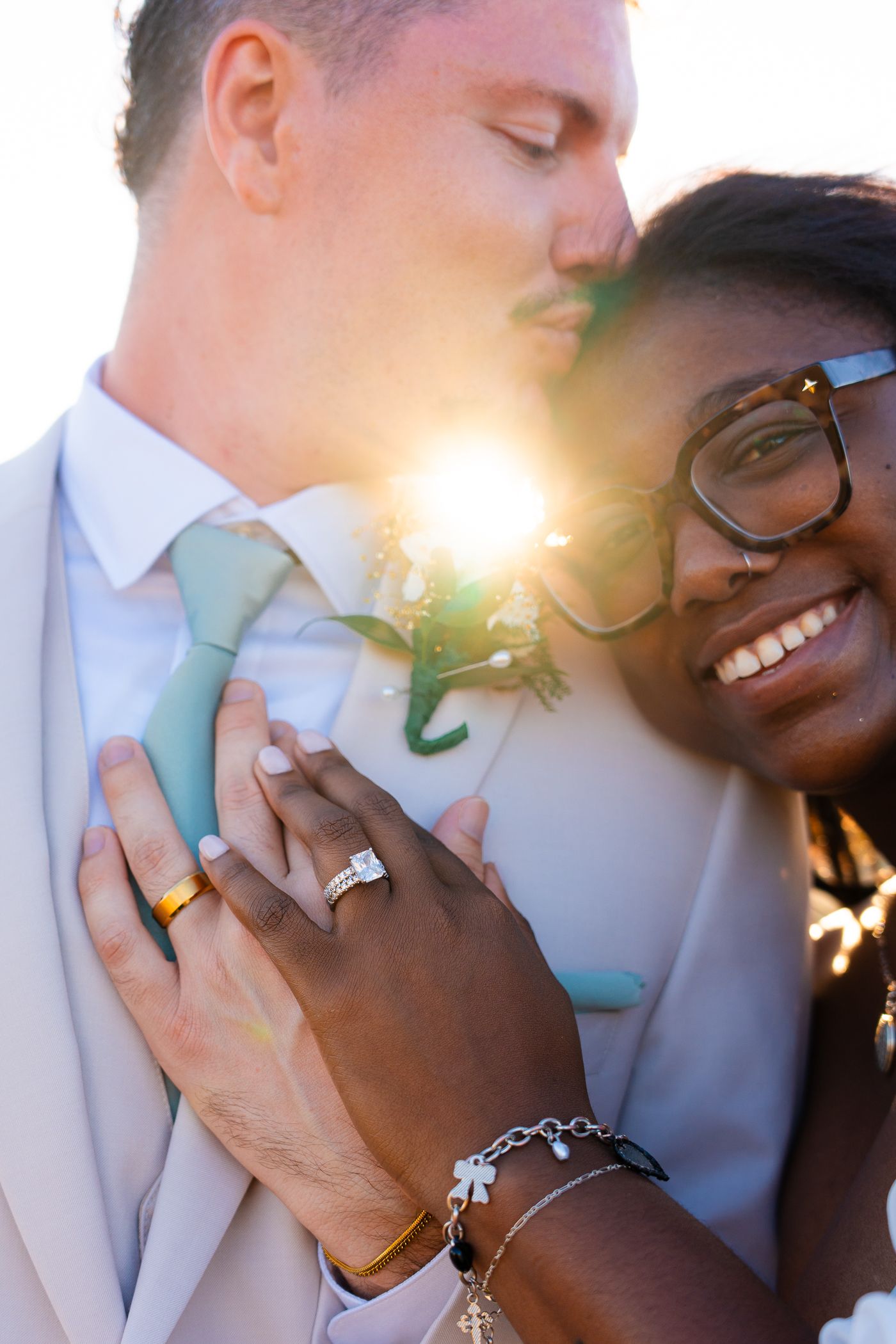 Romantic close-up of a couple sharing an intimate moment at sunset with a beautiful lens flare in the background.