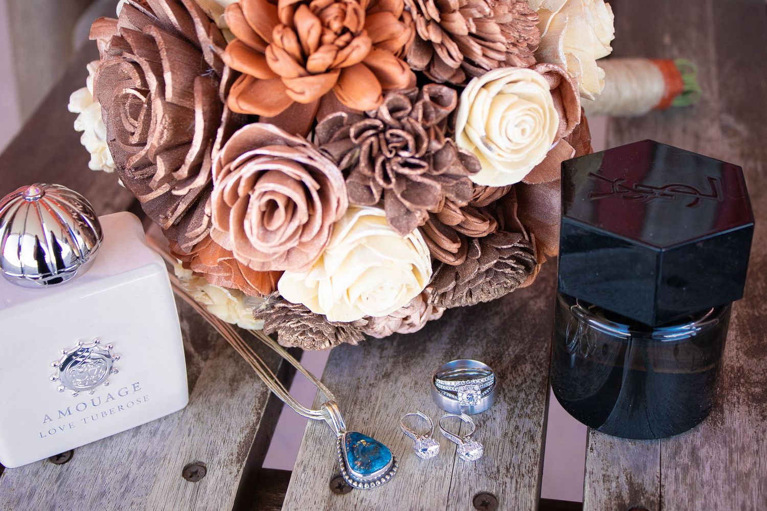 Wedding details featuring vintage roses and jewelry on wooden surface.
