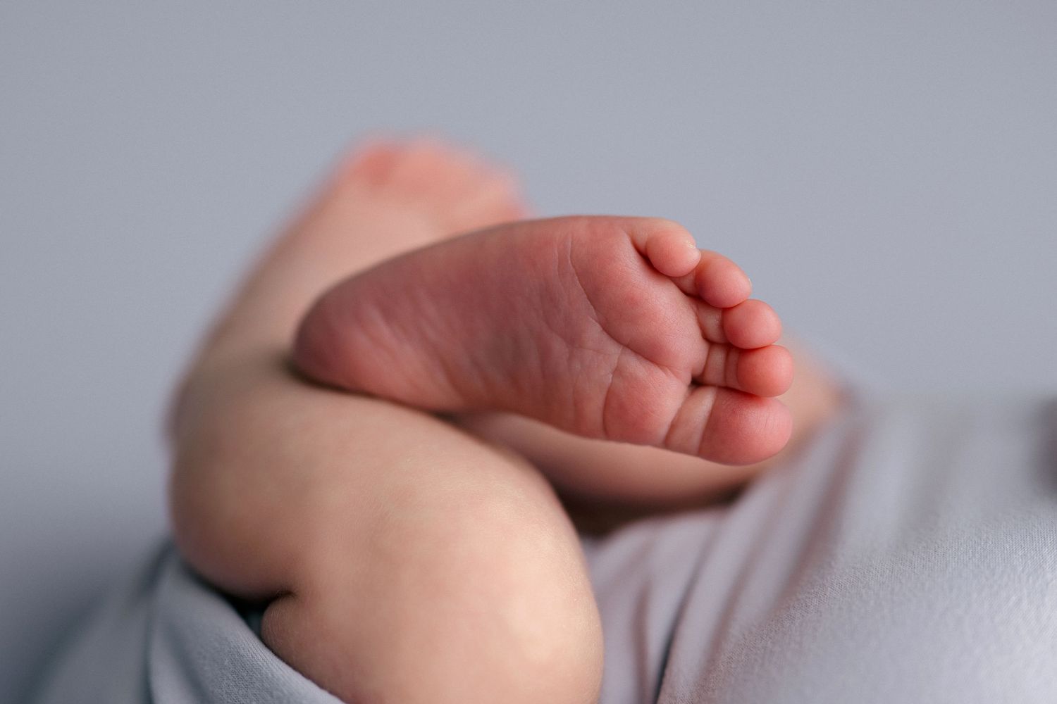 A series of seven cropped photos showing a baby's hands and feet against a light gray background.