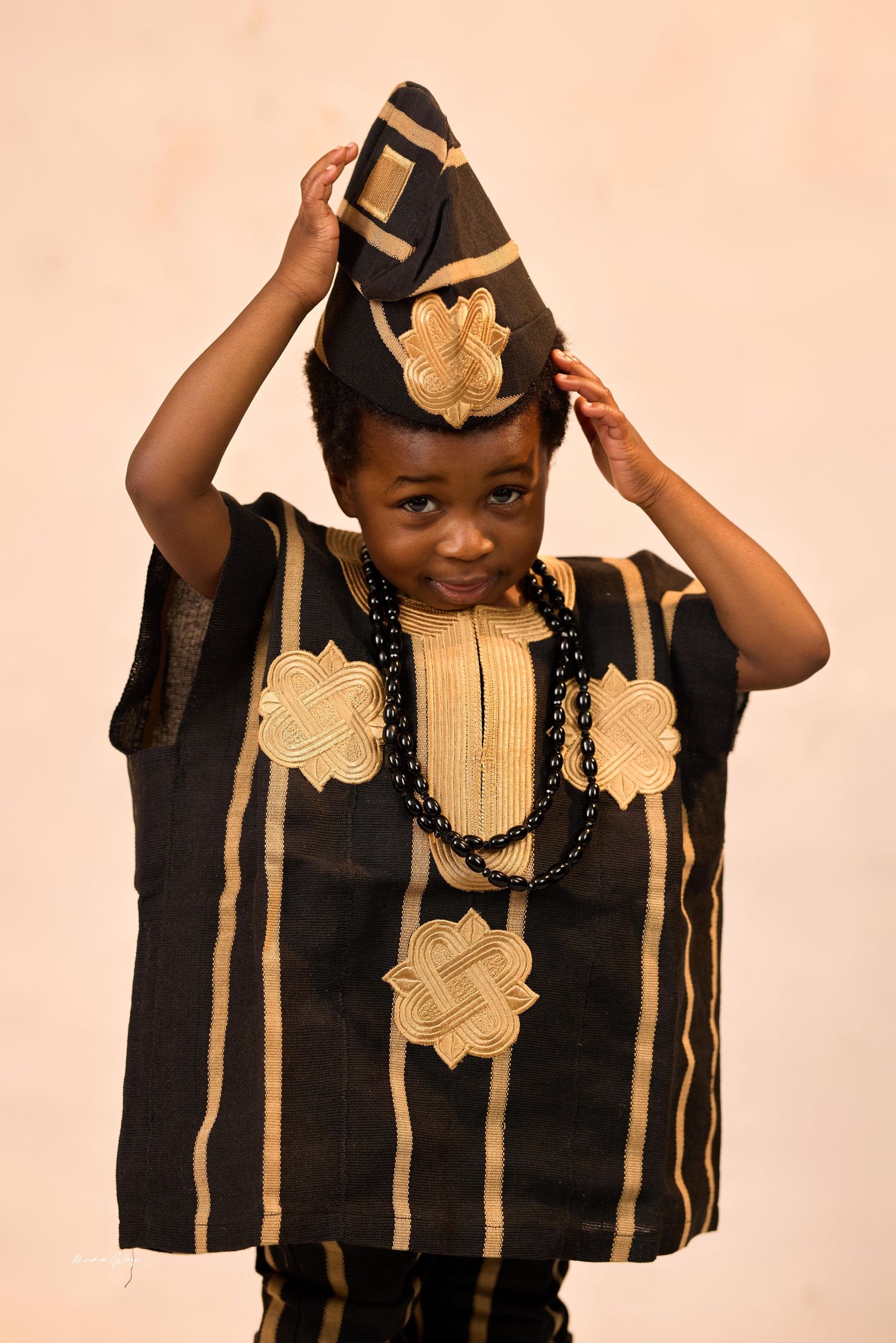 Traditional African attire featuring a black and gold agbada with decorative patterns and matching hat.