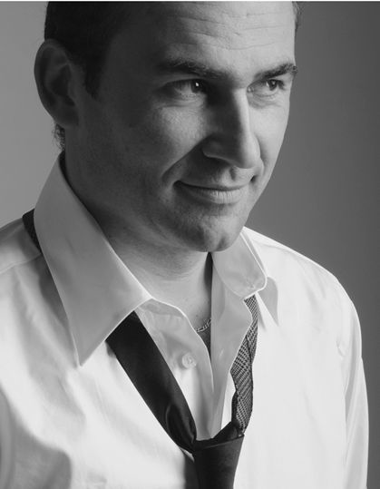 Black and white portrait photograph of someone wearing a white dress shirt and displaying a warm smile.