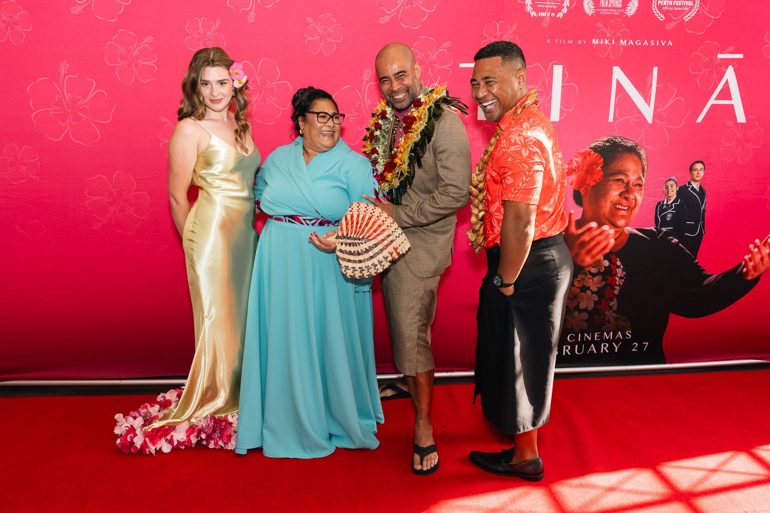The main cast and the director of Tinā standing in front of the media wall for the film.