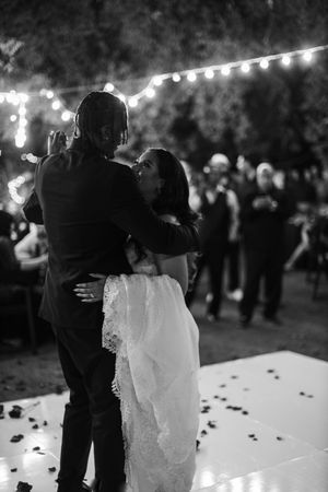 Black and white wedding dance photos show a couple embracing on the dance floor under twinkling lights at night.