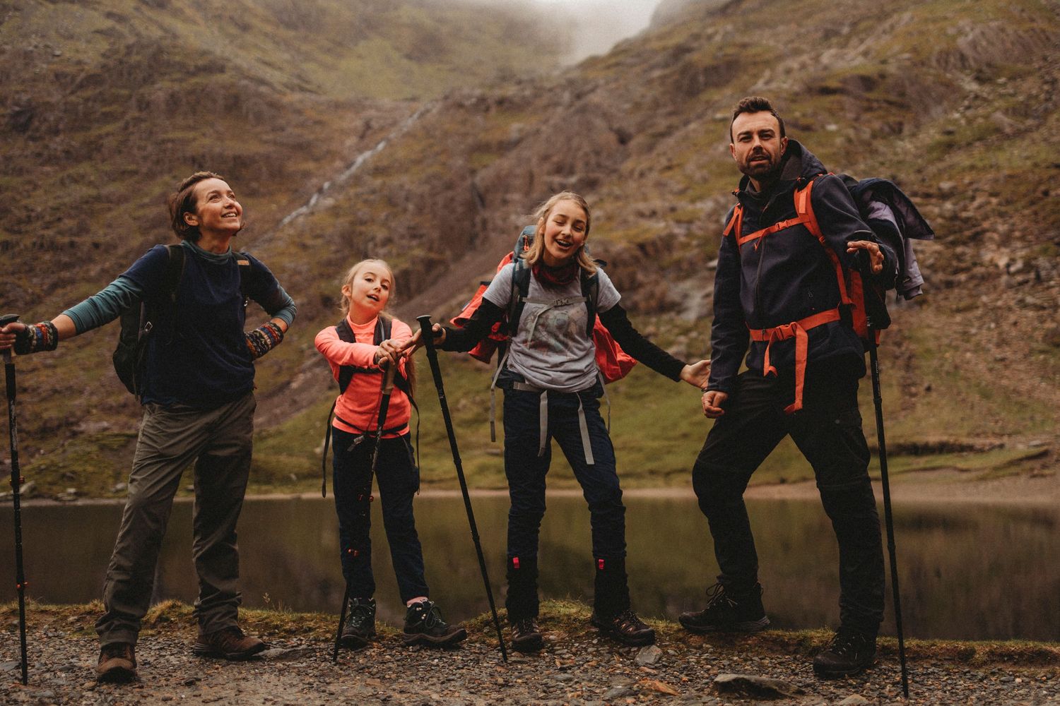 Group of hikers posing together on a mountain trail in misty Scottish highlands.