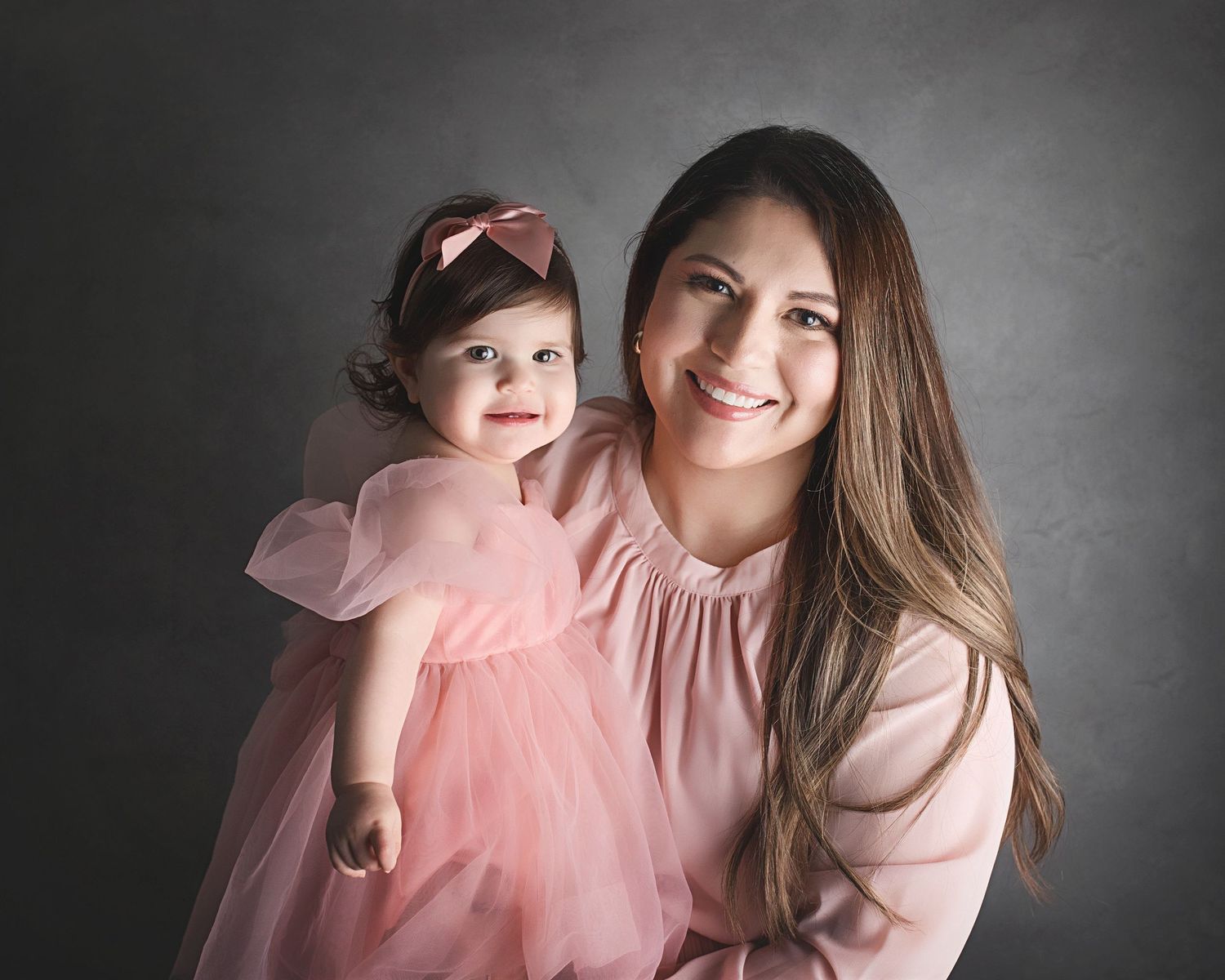 Studio portrait with pink coordinated outfits against dark grey background. San Antonio One Year Cake Smash Photographer