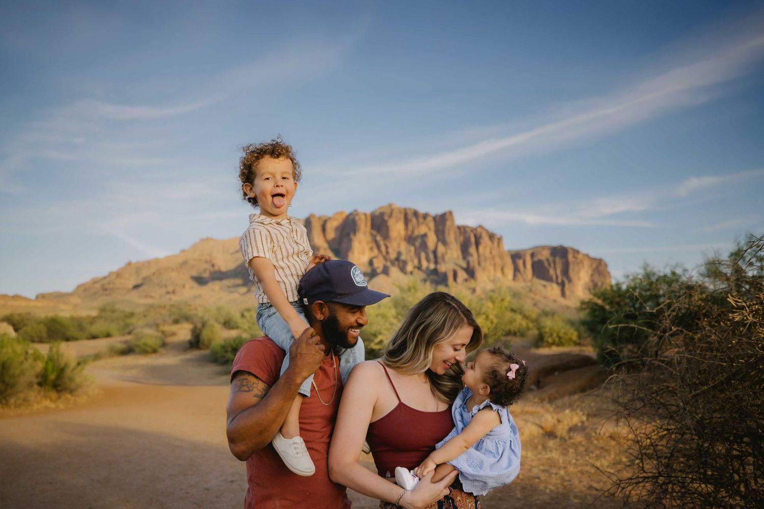 Family of four poses together at golden hour in Arizona desert with saguaro cacti.