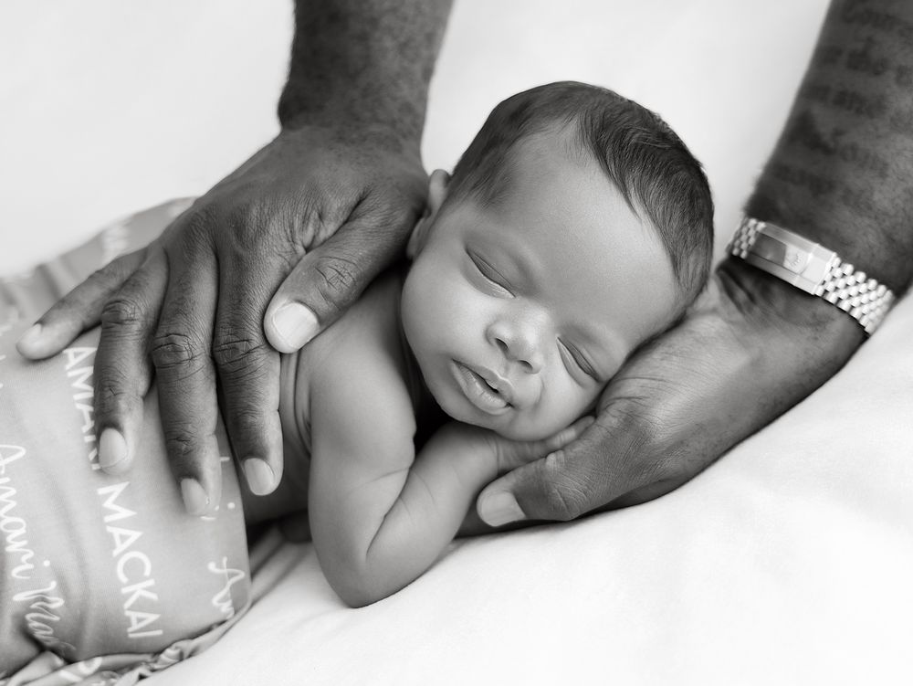 A black and white collage of hands gently holding newborn babies' feet and hands in tender poses.
