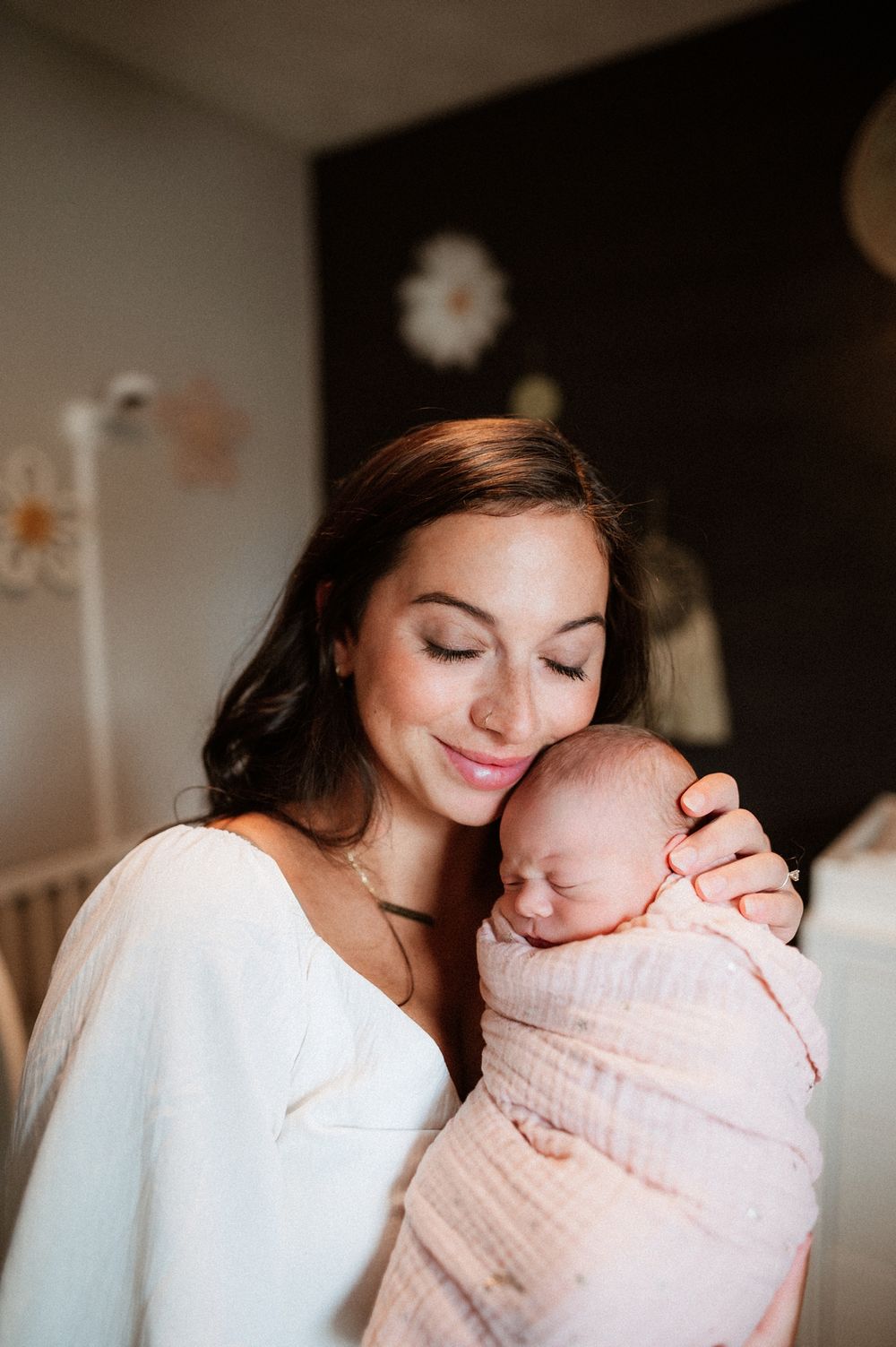 A tender moment with a newborn baby wrapped in soft pink blankets.