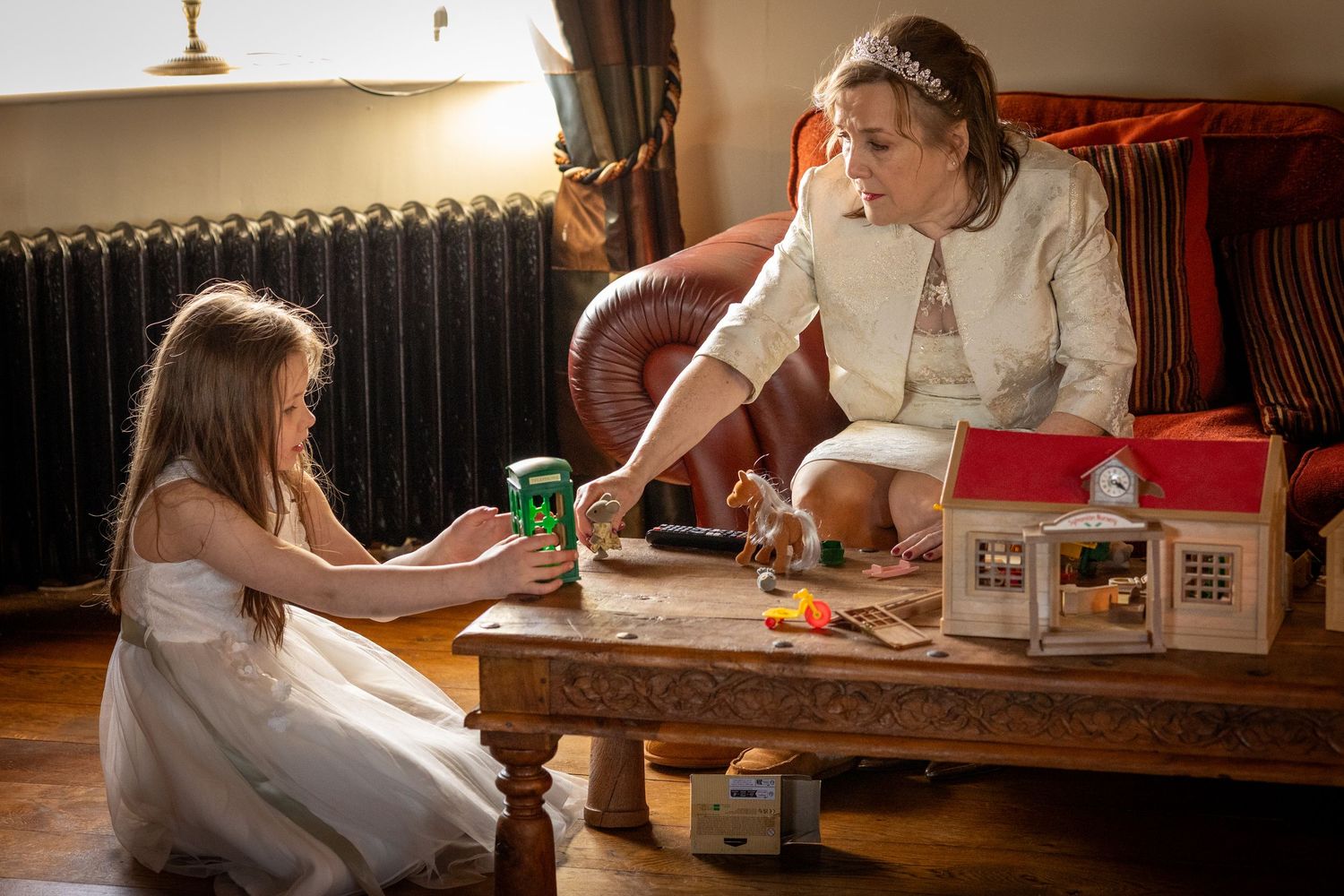 Bride sitting with the flower girl playing with toys inside the windmill at Windmill Farm in Burscough during the wedding day.