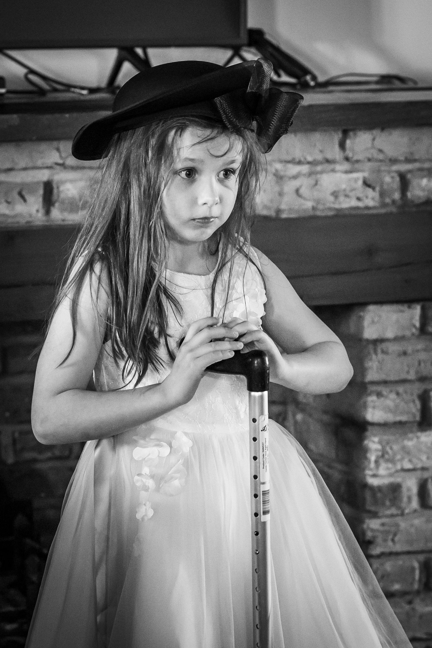 Black and white photo of the flower girl holding a walking cane inside the windmill at Windmill Farm, Burscough wedding.
