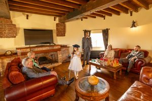Guests relaxing inside the windmill lounge at Windmill Farm in Burscough during a wedding while a flower girl stands with a walking cane.