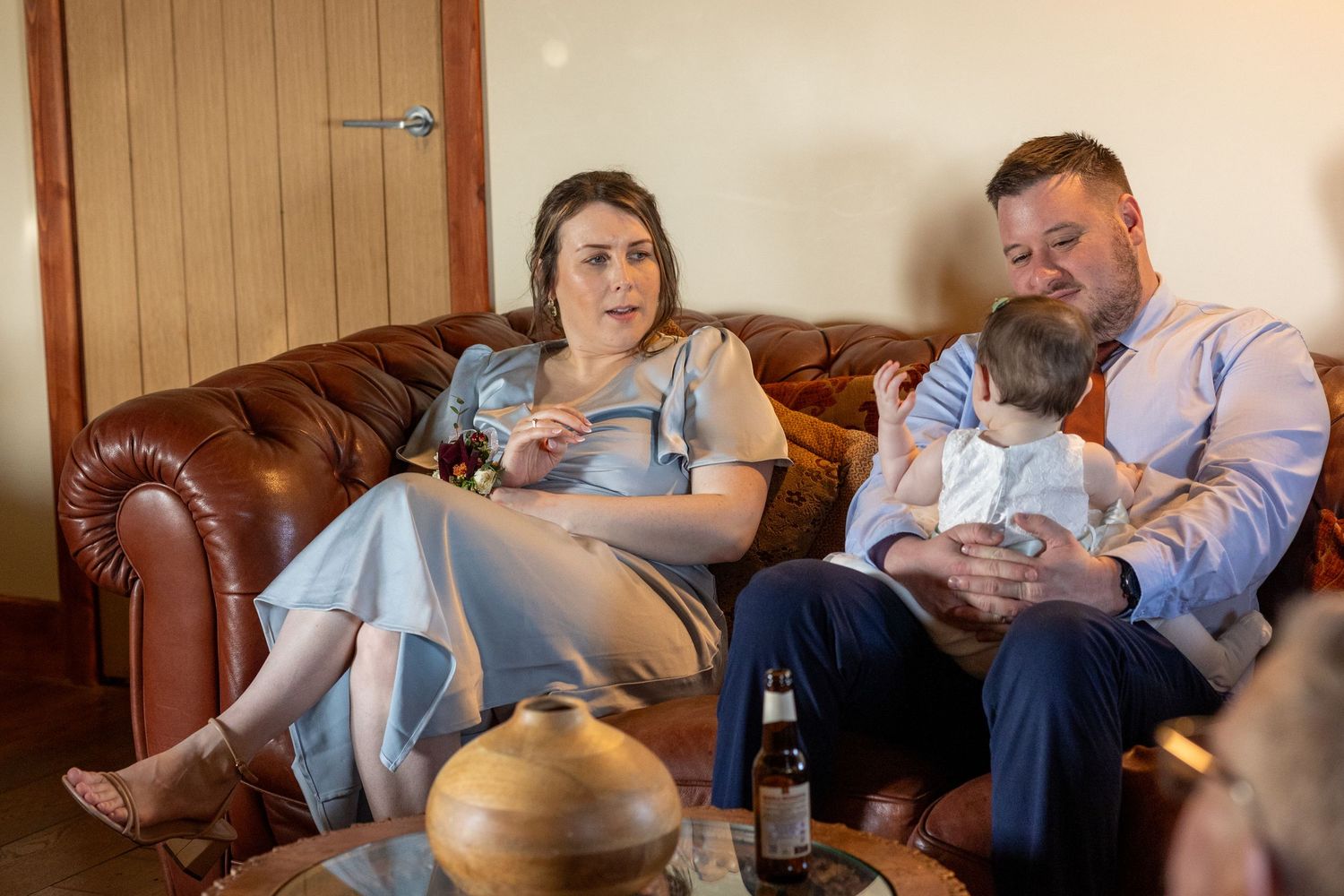Wedding guests relaxing on a leather sofa with a baby inside the windmill at Windmill Farm in Burscough.