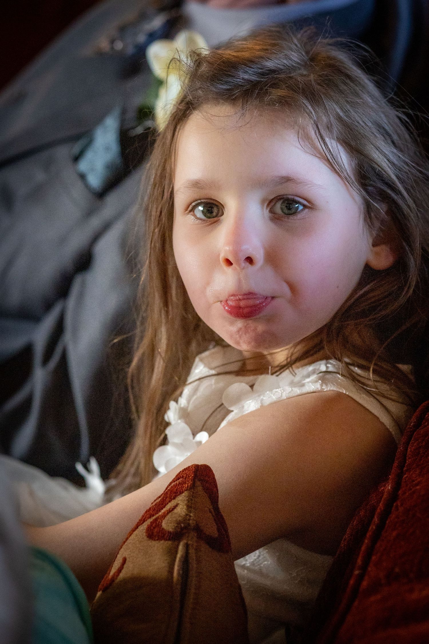 Flower girl pulling tongues and a funny face while sitting on a sofa inside the windmill at Windmill Farm in Burscough.