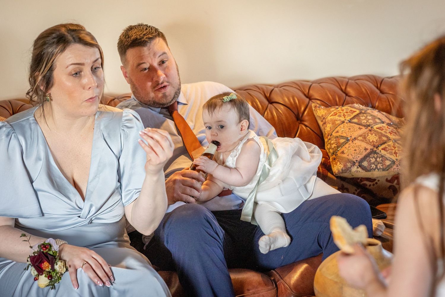 Baby holding a beer bottle while sitting with parents on a sofa inside the windmill at Windmill Farm in Burscough.