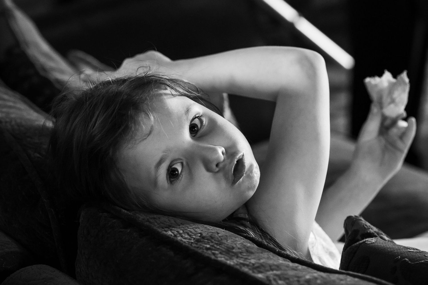 Flower girl lying on a sofa pulling a playful face during a quiet moment inside Windmill Farm in Burscough.