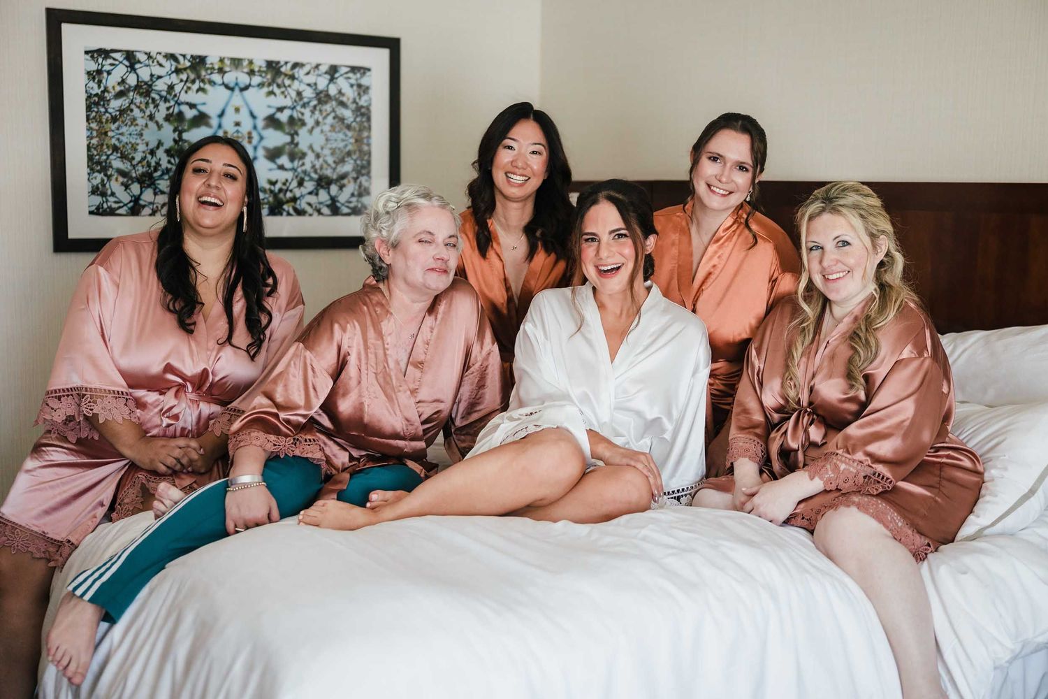 Bride and bridesmaids relaxing together during wedding morning preparations in Boston