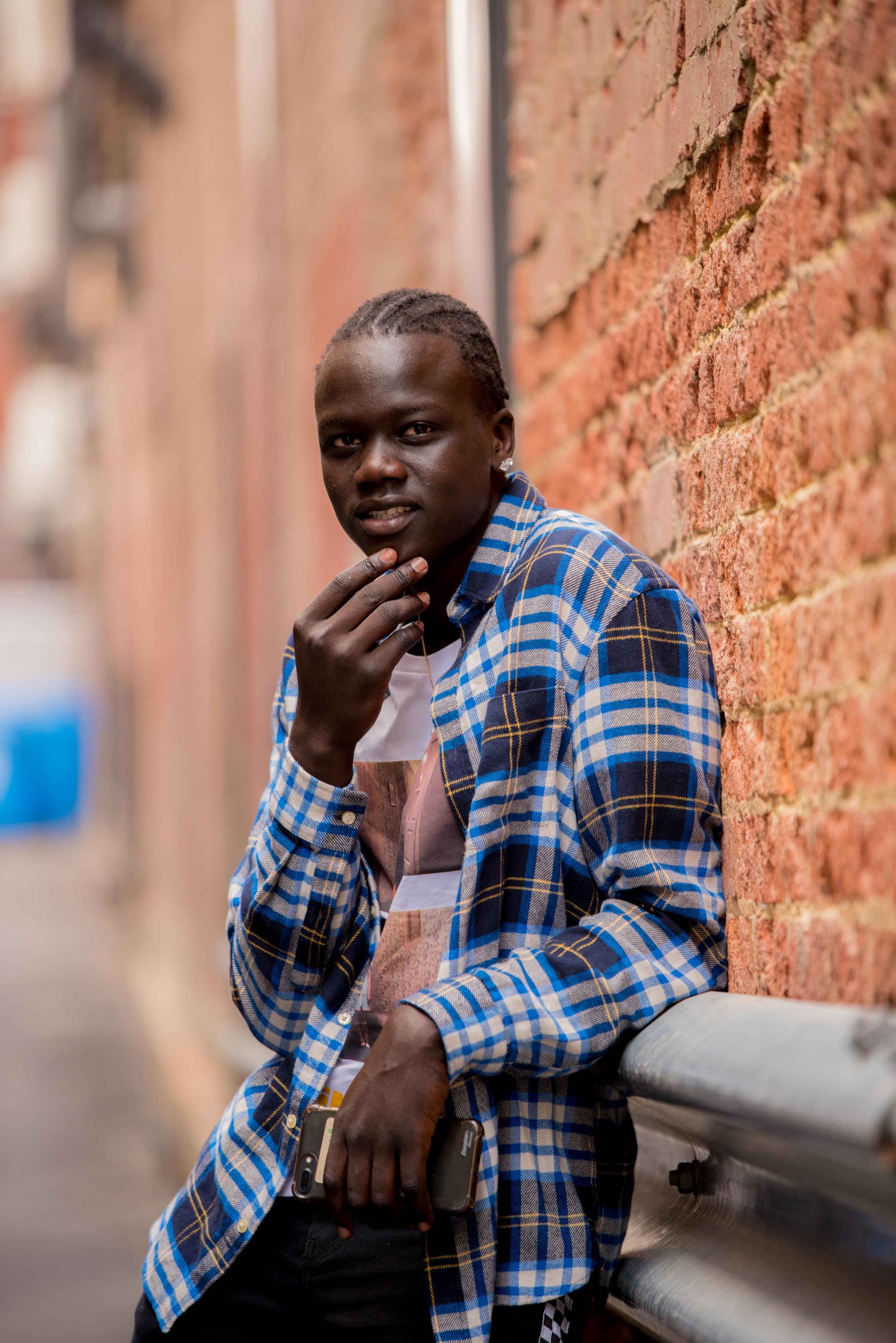 A series of emotional expressions shown in a plaid shirt against a brick wall background.