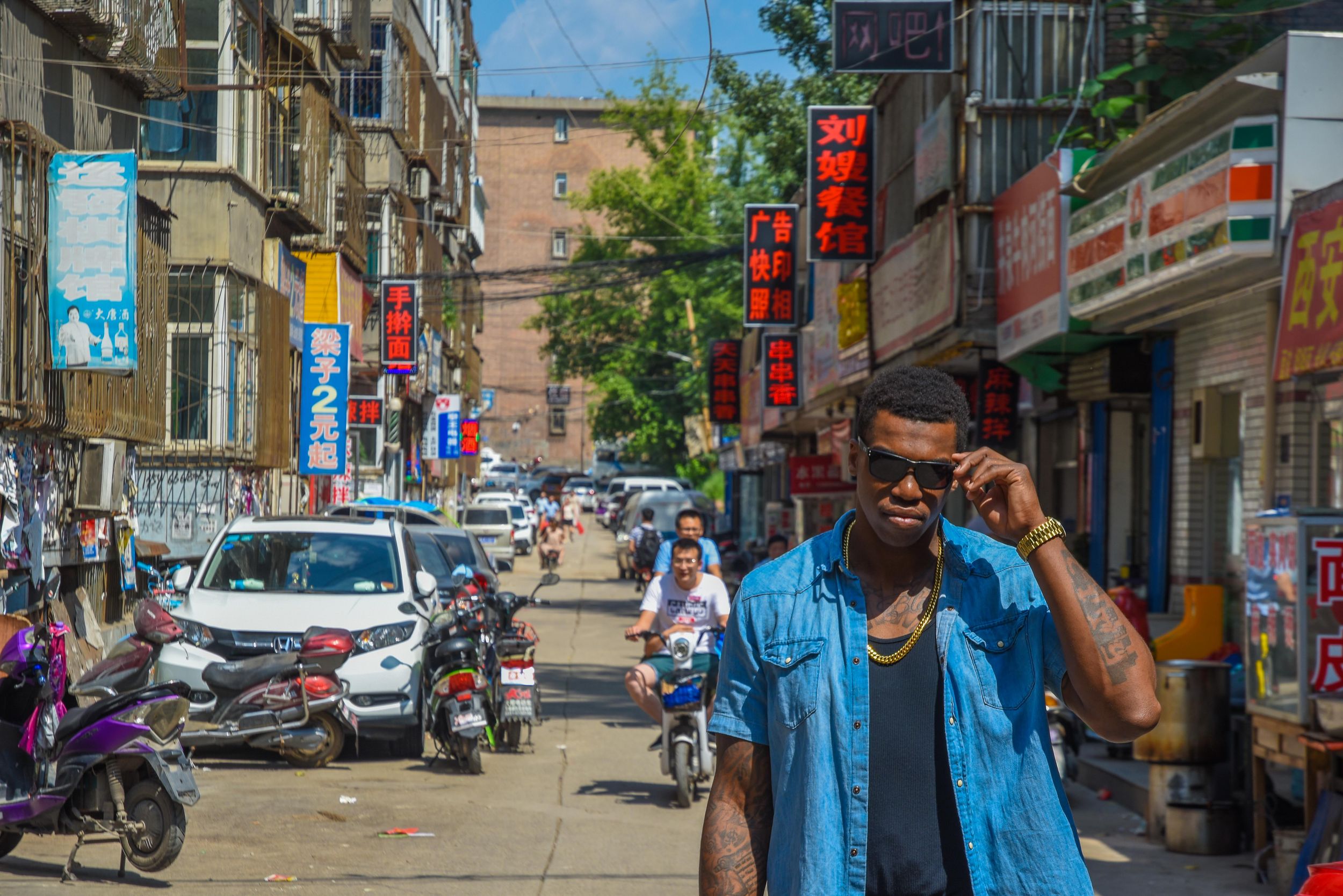 Person in denim jacket on busy urban street with red lanterns and storefronts in Shanghai.