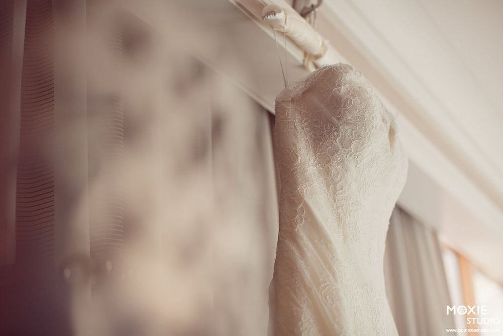 Close-up detail of an elegant white lace wedding dress hanging on display.