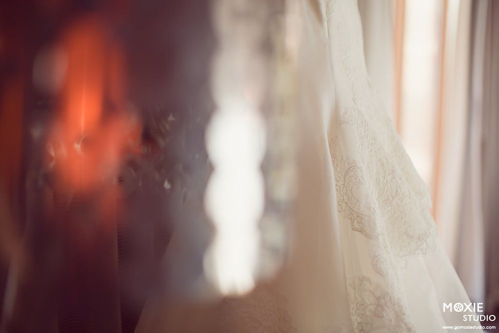 Soft focus artistic photo showing blurred wedding dress details in warm lighting.
