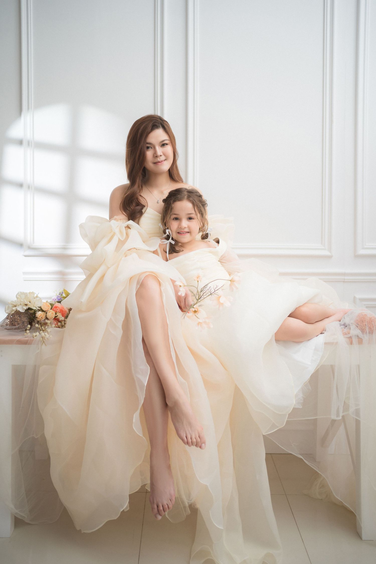 A tender maternity moment by a window as an expectant mother in a flowy dress shares a special moment with her partner.