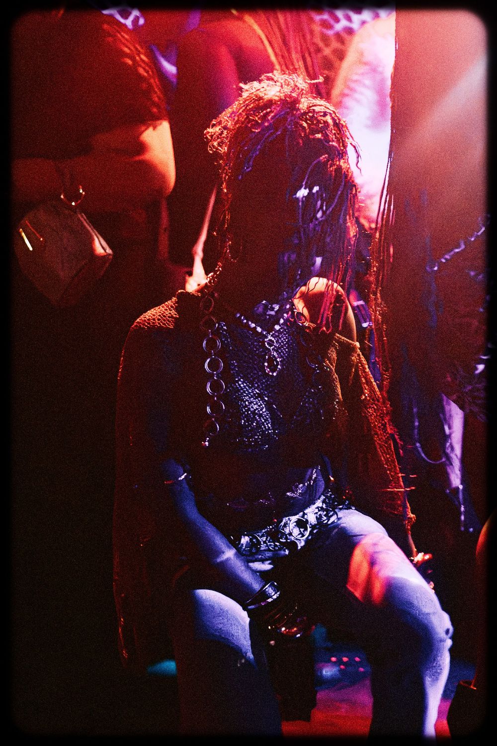 Rock band performs on stage with dramatic red and blue lighting creating a moody concert atmosphere.