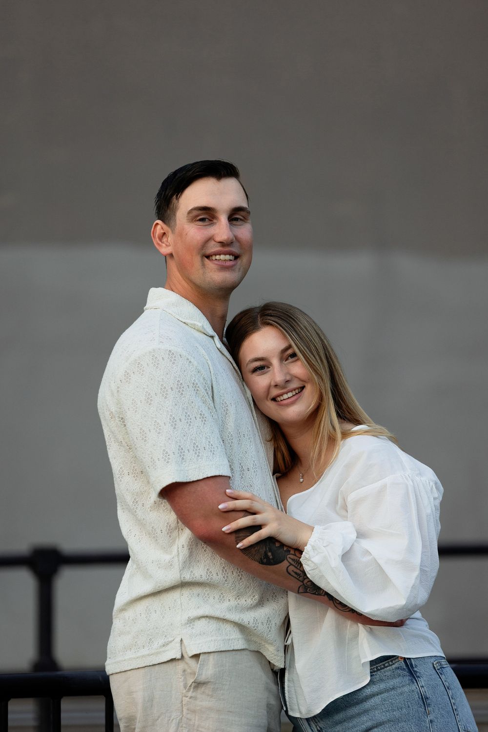 A couple in white tops and jeans share a romantic moment during an engagement photo session.