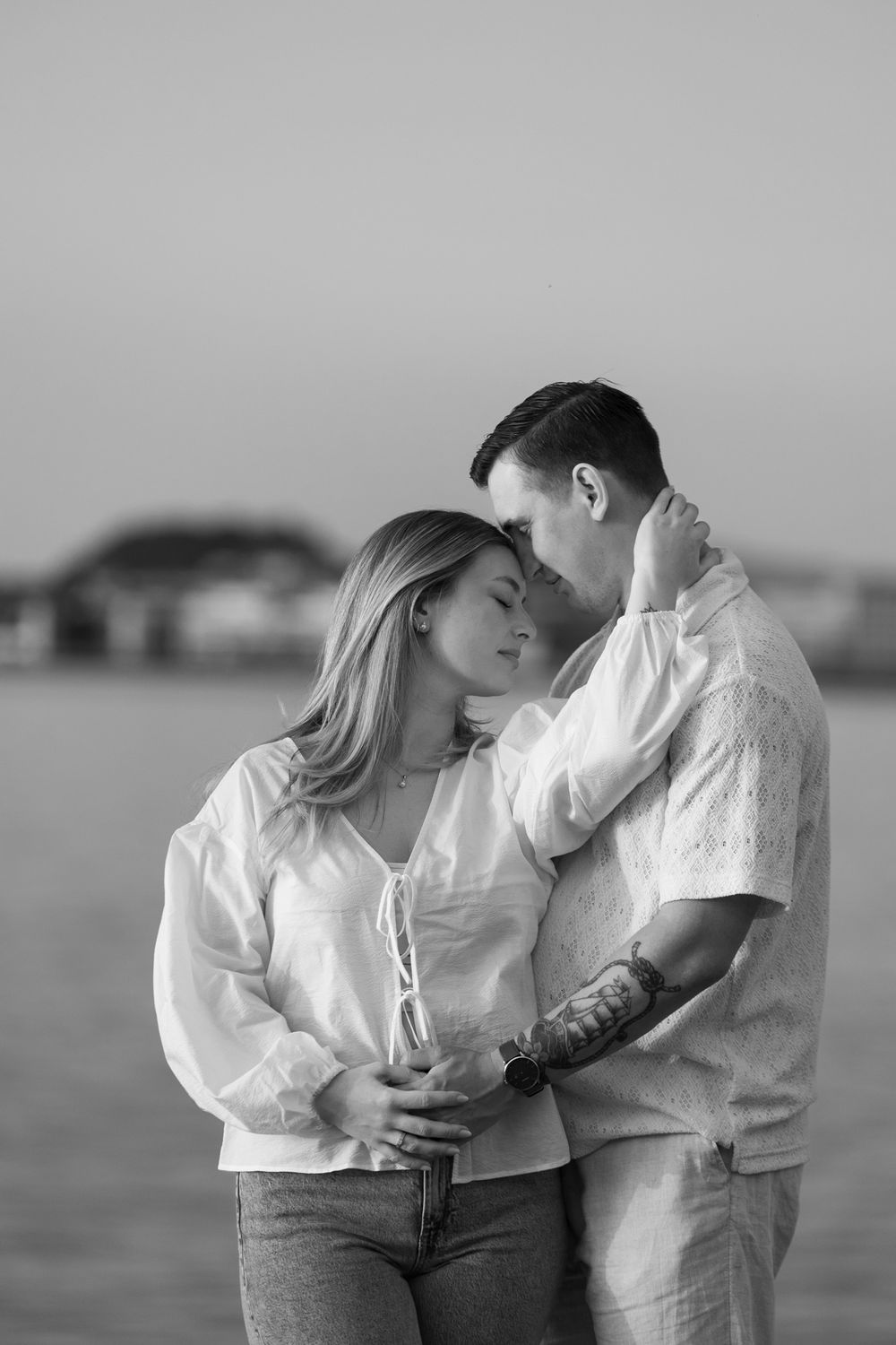 A romantic black and white photo sequence showing a couple in intimate embraces by the water.