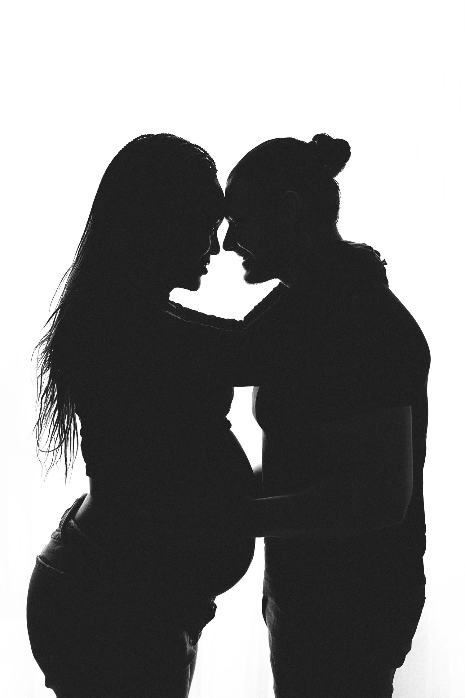 A pregnant woman in a white dress poses gracefully in a series of artistic maternity photos against a light background.