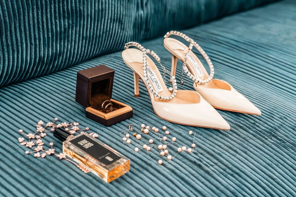 White bridal shoes and pearl necklace arranged with vintage wooden box on blue wooden background.