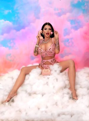 Fantasy boudoir photo on clouds with pink and blue sky backdrop.