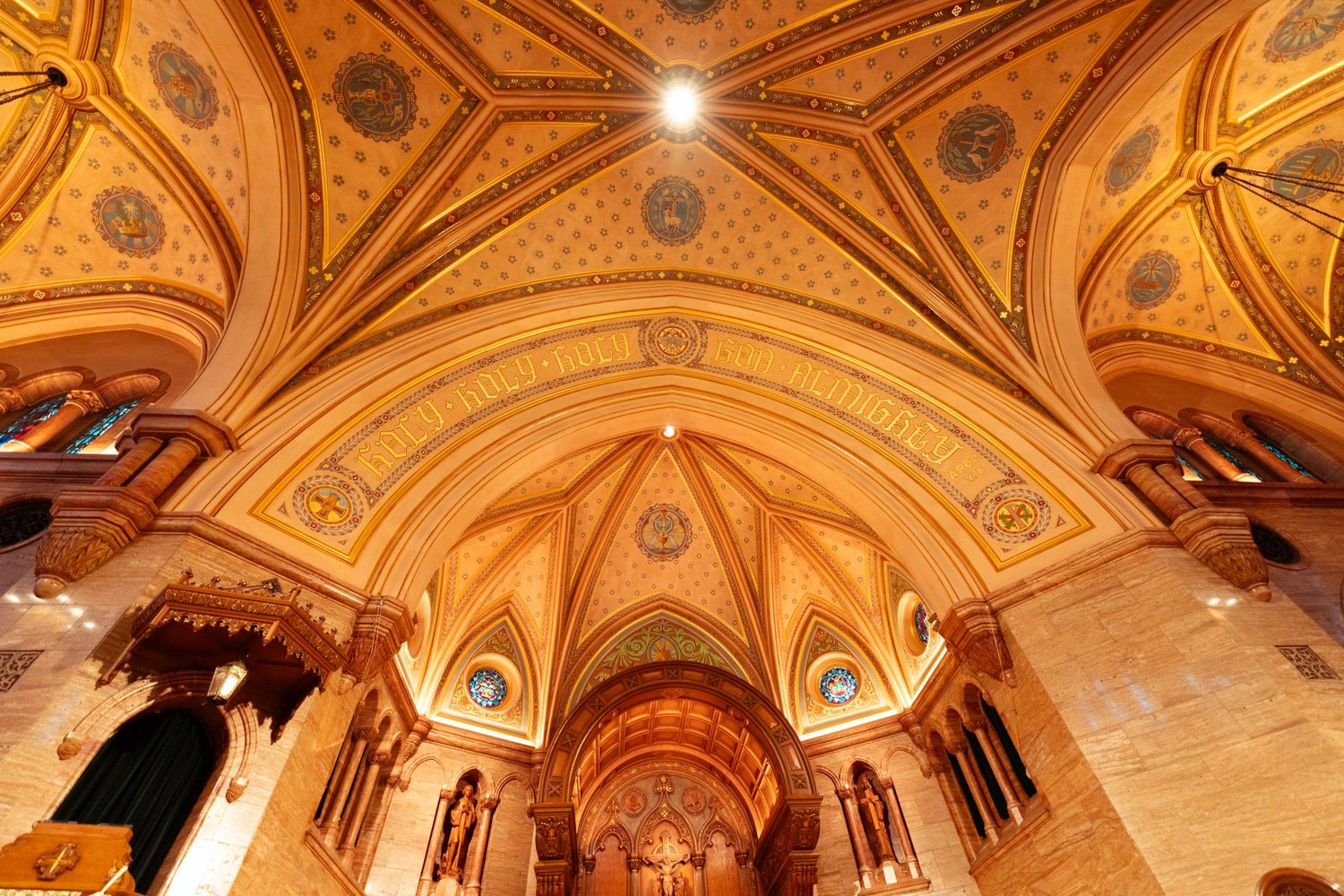 Ornate golden ceiling with intricate architectural details and domed arches in a historic building interior.