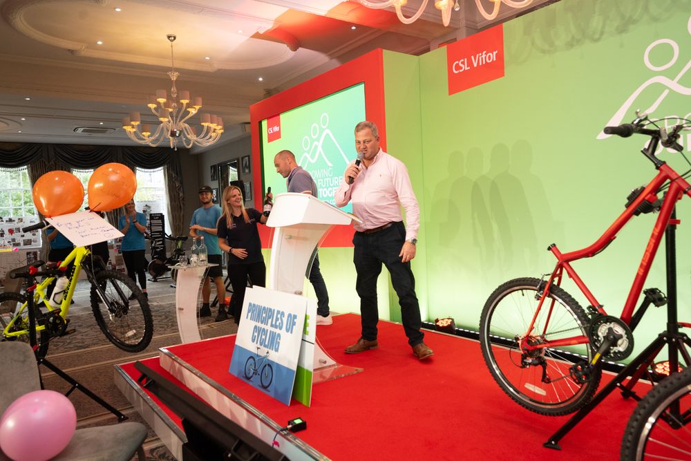 A series of exercise bikes and fitness equipment arranged in a modern gym with red and green walls.