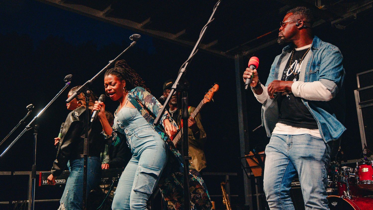 Dynamic performer in light blue jacket energetically singing on stage during a live music concert performance.